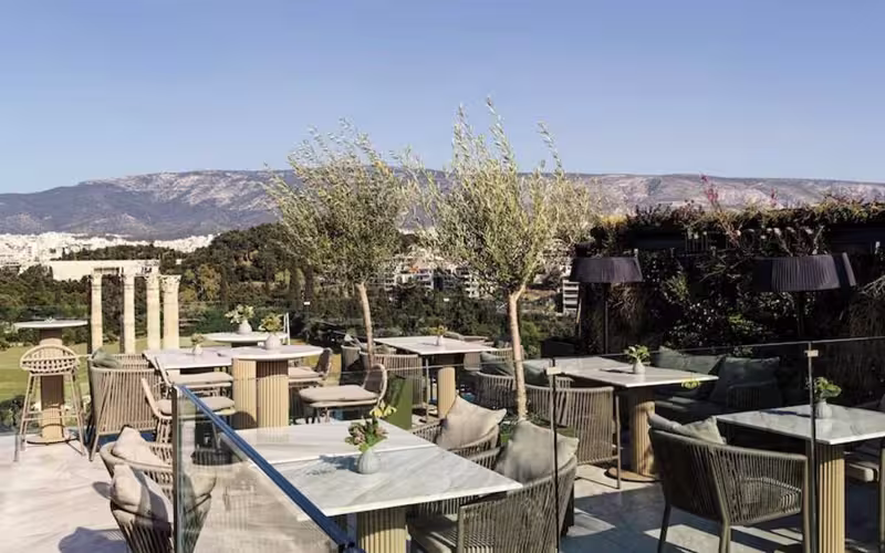 Dakterras met gedekte tafels en uitzicht op de Akropolis