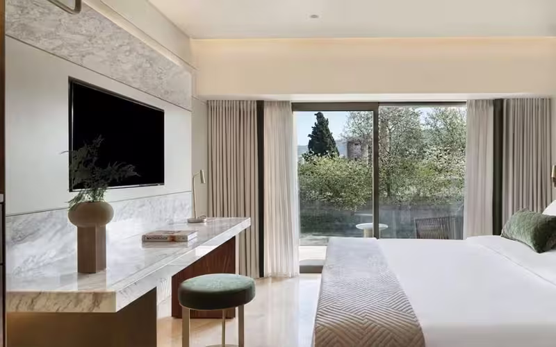 Hotelkamer met bed, bureau en openslaande deuren naar het balkon