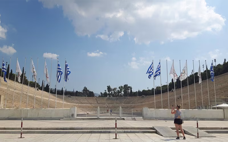 Het Panathinaiko-stadion met de vlaggenmasten en een hardloper op de baan