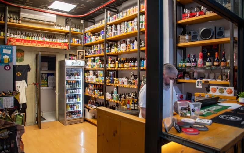 Het interieur van Brew Street met schappen vol bierflessen en koelkasten