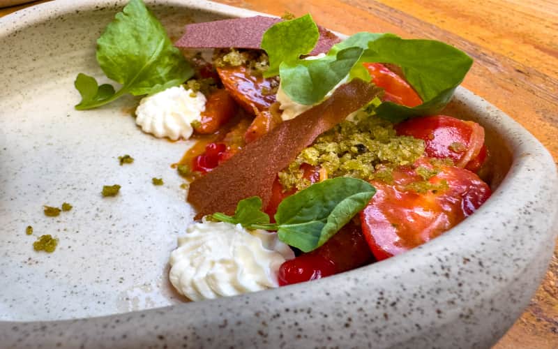 Gerecht met gerookte tomaat, room en verse kruiden op een stenen bord