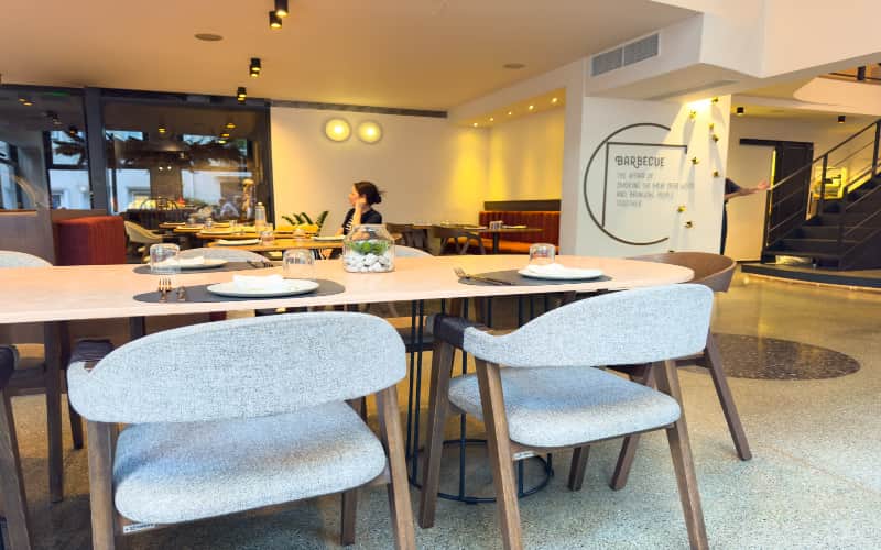 De eetzaal van Fine Mess Smokehouse met lichte stoelen en gedekte tafels