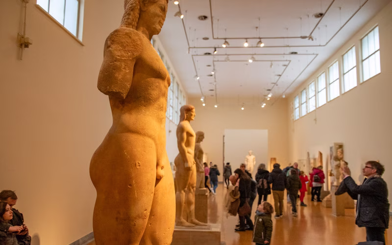Beeldenzaal in het Nationaal Archeologisch Museum met bezoekers tussen de marmeren beelden