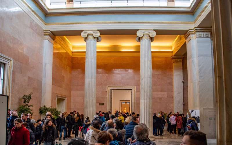 De zuilenhal bij de ingang van het Nationaal Archeologisch Museum met wachtende bezoekers