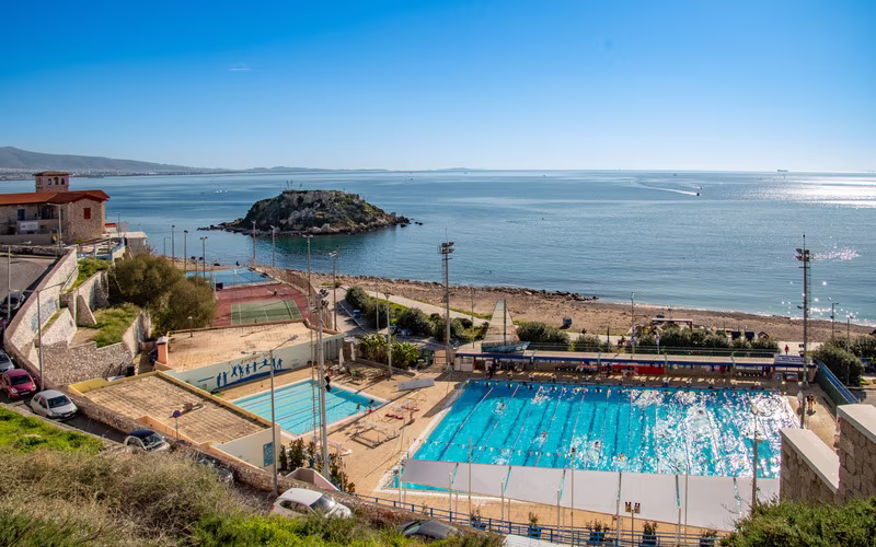 Zwembadcomplex aan de kust bij Piraeus met de zee en een eilandje erachter