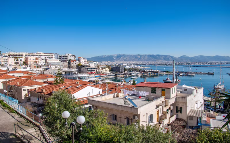 Uitzicht over de daken van Piraeus naar de haven en de bergen