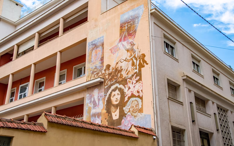 Muurschildering in okertinten op de gevel van een appartementengebouw in Athene