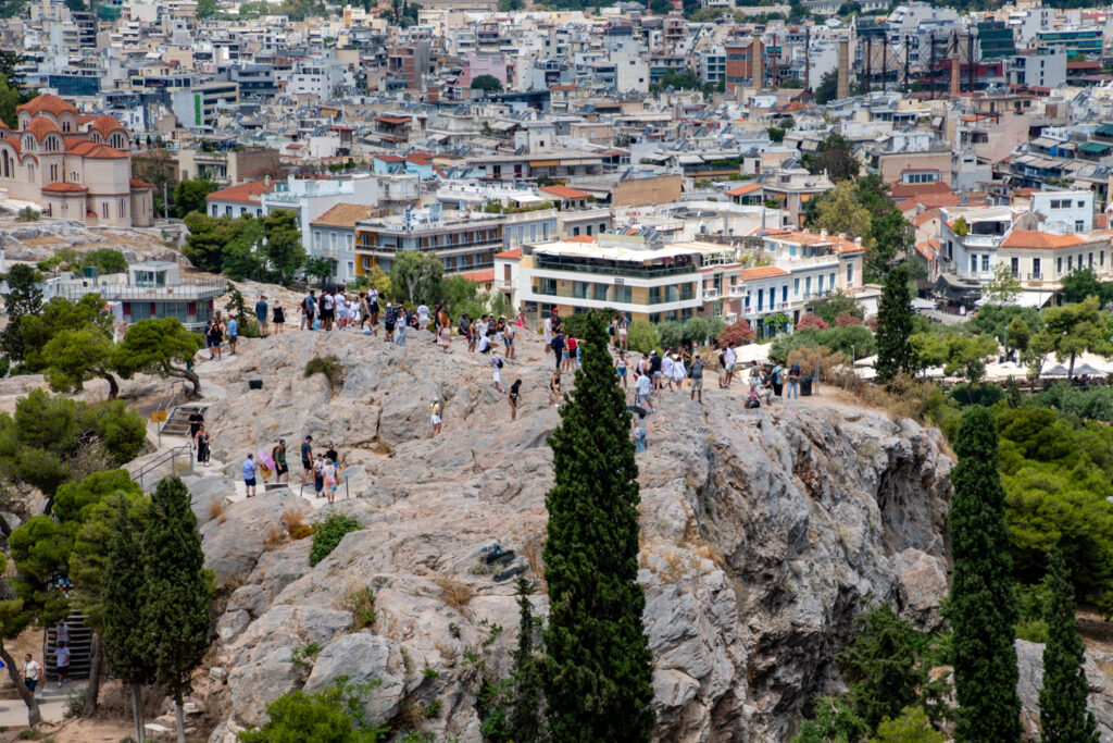Uitzicht vanaf de Areopagus over de daken van Athene, met bezoekers op de rots