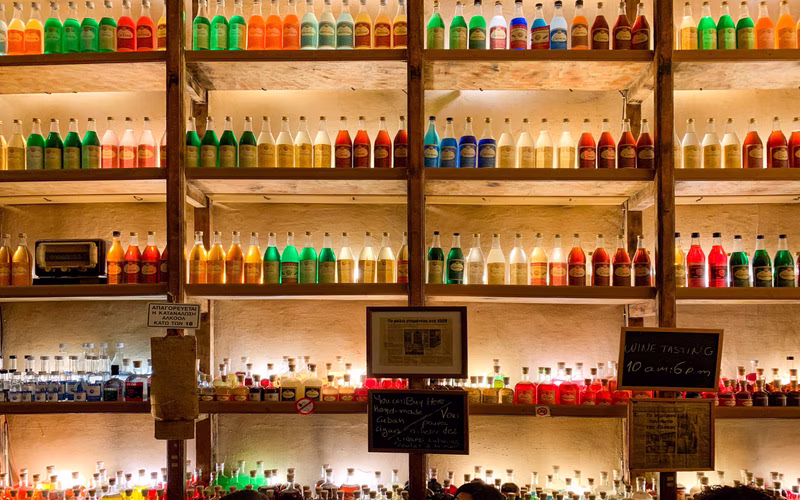 Schappen vol gekleurde flessen in de bar van Brettos in Plaka