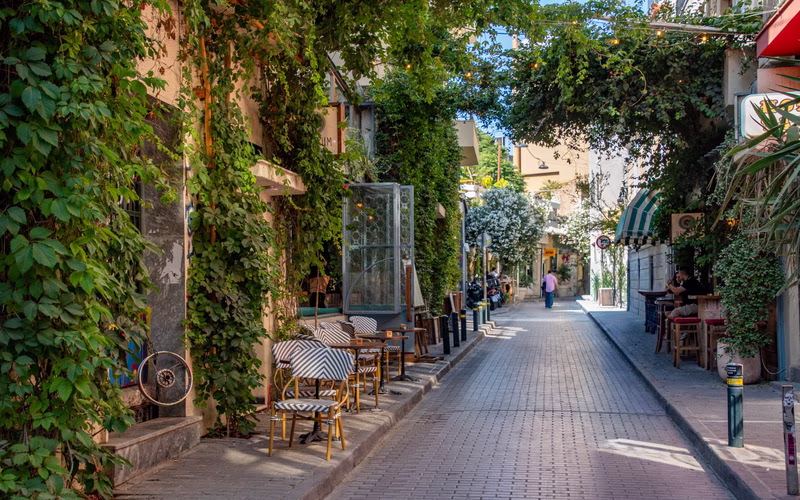 Met klimplanten overgroeide straat in Psirri met terrastafeltjes