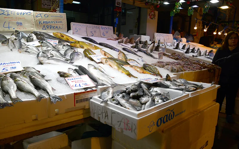 Uitgestalde vis op ijs in de vismarkt van Athene, met handgeschreven prijskaartjes bij de zeebaars en de sardines