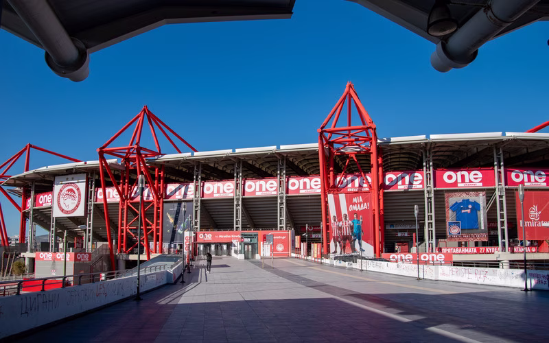 Het Georgios Karaiskákisstadion in Neo Faliro met de rode staalconstructie en de vlaggen van Olympiakos